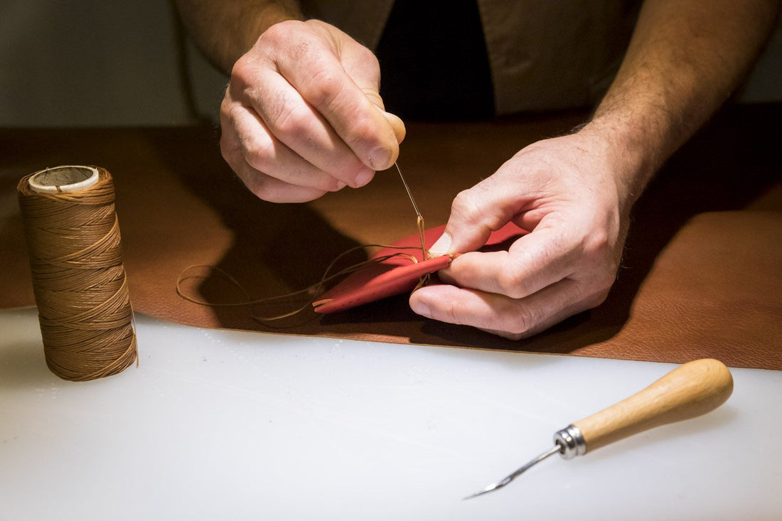 Franco's hands saddle-stitching a leather piece at the Gli Aminti atelier in San Gimignano